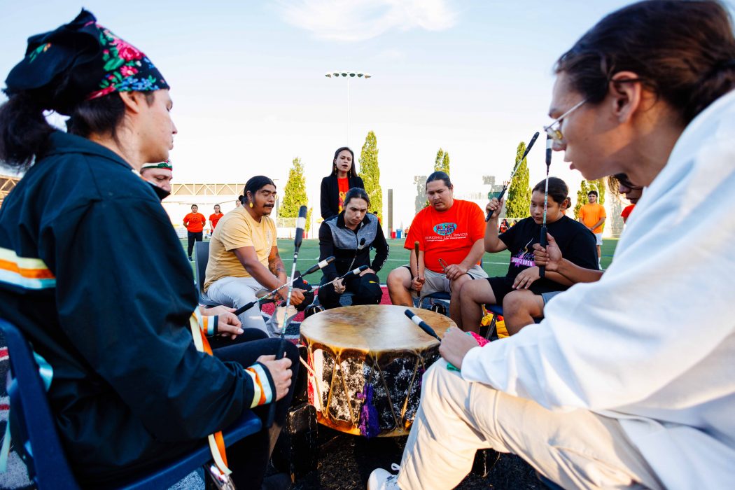 A group of people sit in a circle drumming.