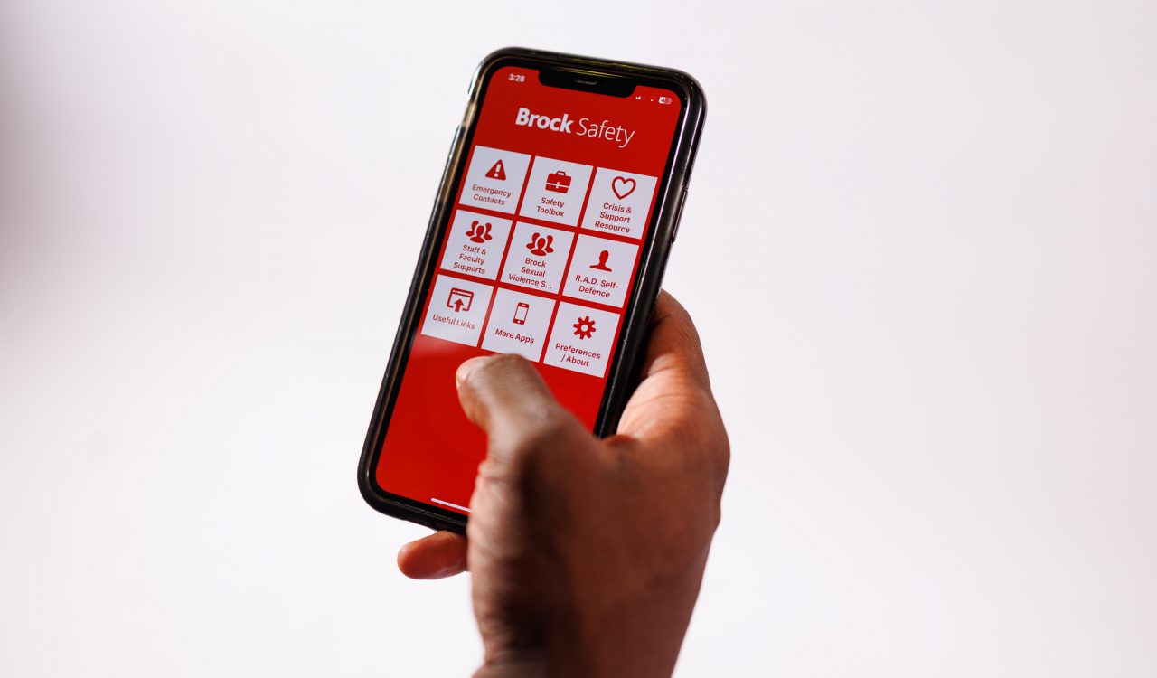 Close-up of a hand holding a phone with a red and white app displayed on the screen.