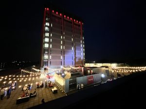 Brock's Schmon Tower lit up in red at night with string lights glowing around the base during an outdoor event.