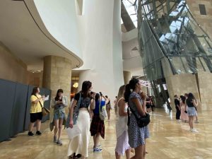 A group of university students wander and look up at a museum lobby with intricate architecture and high ceilings.