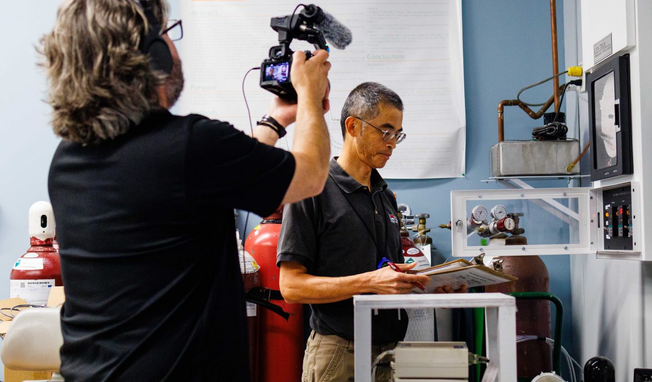 Stephen Cheung is interviewed by the CBC's cameraman while working in his lab at Brock University