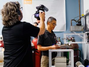 Stephen Cheung is interviewed by the CBC's cameraman while working in his lab at Brock University