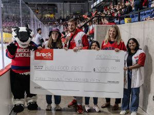 Five people and a badger mascot stand with a large cheque for $3,250 for the BUSU Food First program.