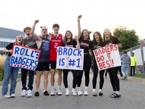 A crowd of people holding Brock University signs supporting the Badgers stand together outside.