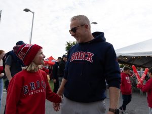 A child and adult look up at one another, both wearing Brock University sweatshirts.