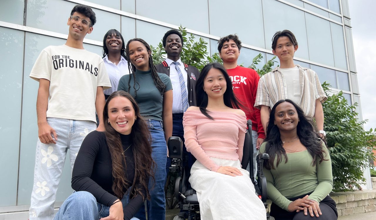 Brock University’s nine international student ambassadors pose for a group photo outside of the Brock International Centre building.