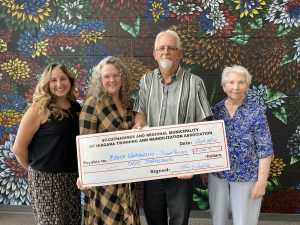 Four people stand together holding a large cheque.