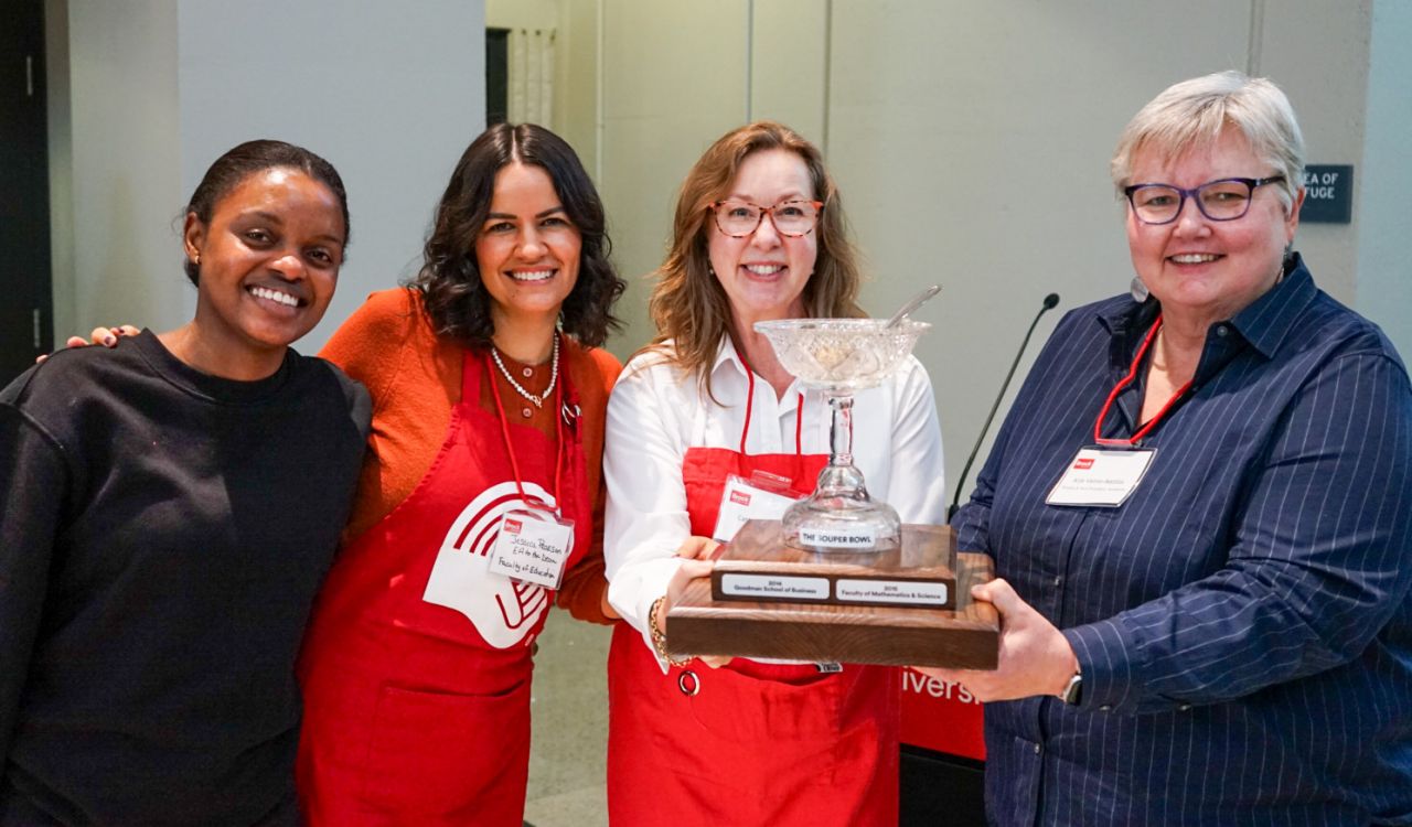 Four women pose with a trophy.