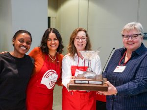 Four women pose with a trophy.