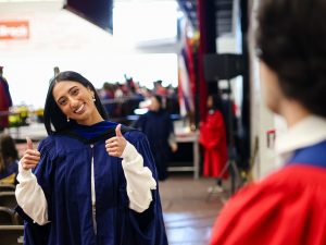 A graduate gives a thumbs-up after exiting the Convocation stage.