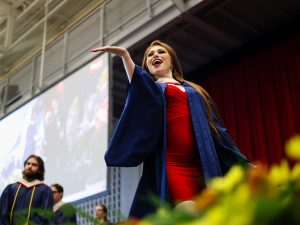 A graduate waves to the crowd from the Convocation stage.