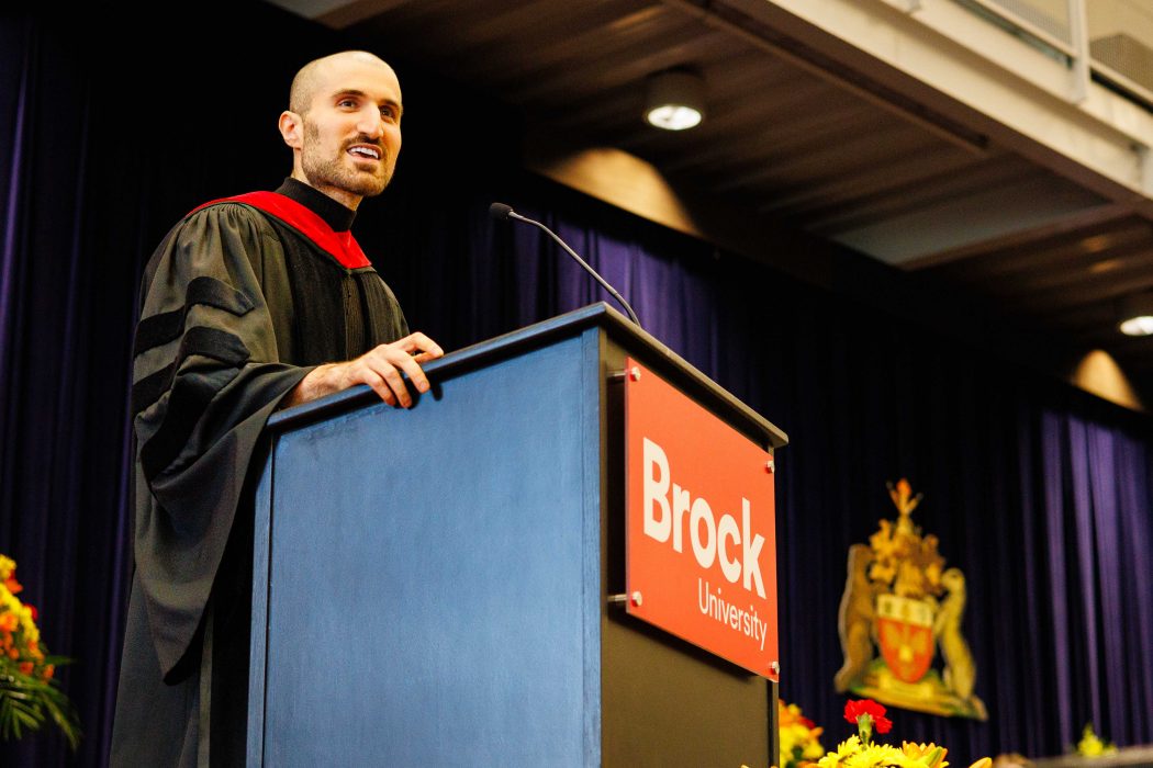 Assistant Professor of Computer Science Ali Emami wears a blue convocation gown and delivers a speech during the morning ceremony of Brock University's 116th Convocation.