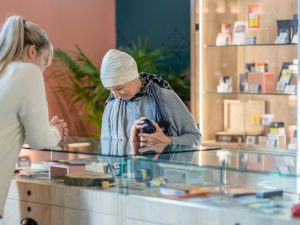 Woman wearing a hat shops in a cannabis store with the assistance of a store clerk behind the counter.