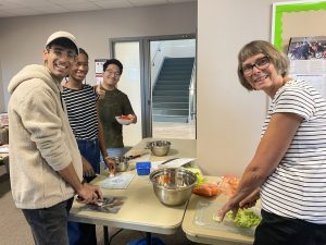 Four people stand around a table preparing a meal.