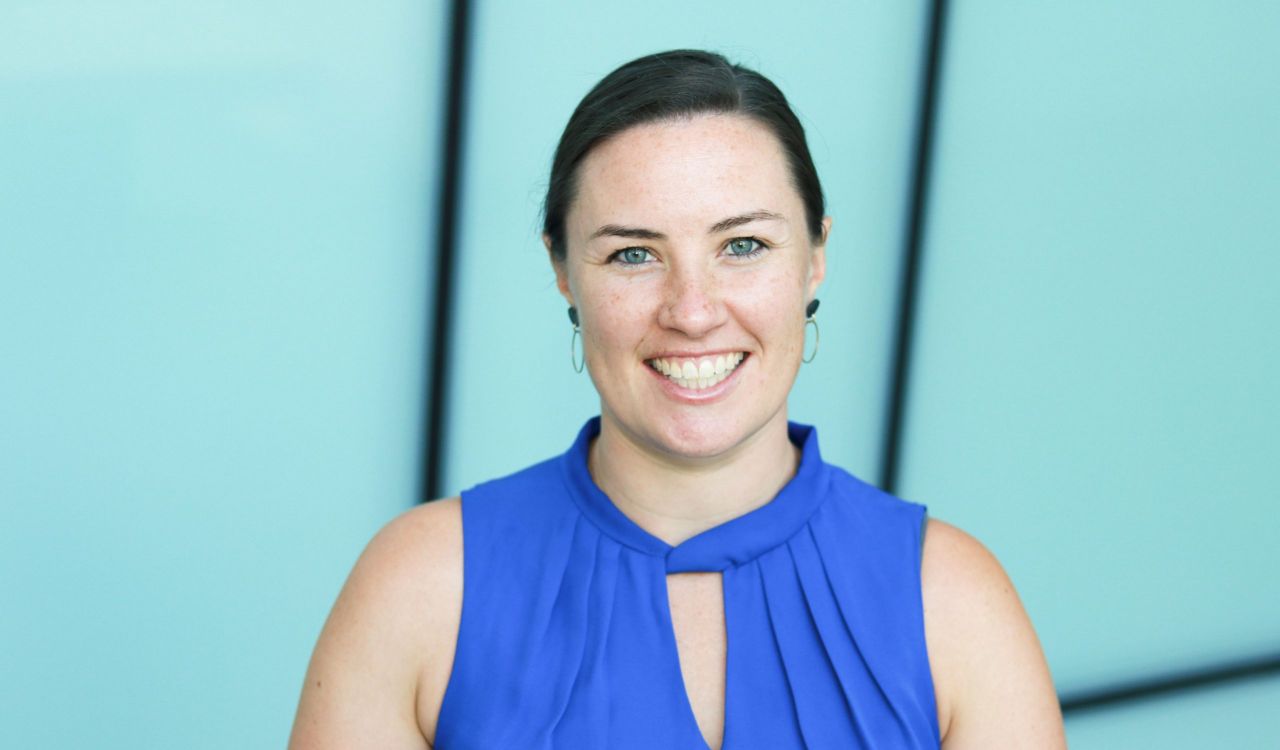 A woman in a blue shirt poses for a photo.