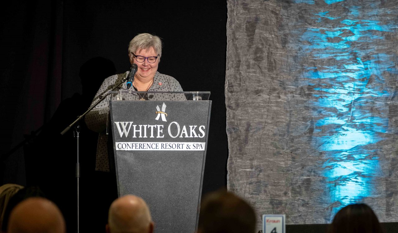 Brock University’s Provost and Vice-President, Academic Arja Vainio-Mattila smiles while delivering a speech behind a podium.