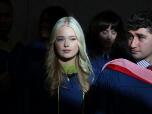 A group of graduates stand together in a dark room.