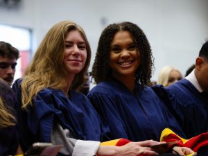 A group of graduates sit together smiling.