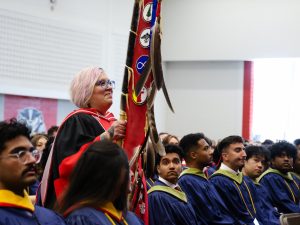 A woman carriers the sacred eagle staff that leads Brock's Convocation procession.