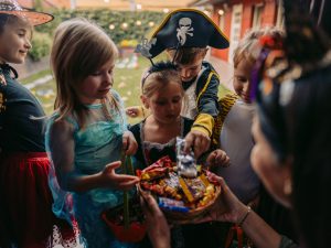 Children dressed in Halloween costumes gather on a doorstep to collect candy.