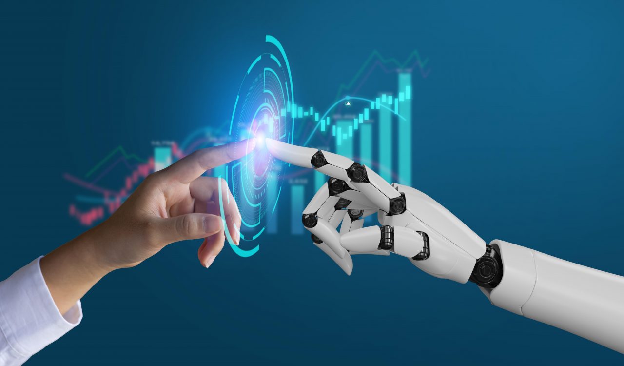 A human hand reaches to touch the hand of a robot, their index fingers nearly touching. In between their fingers is a digital illustration of a spiral made up of many rectangles in an irregular pattern. In the background is an out-of-focus line graph and bar chart.