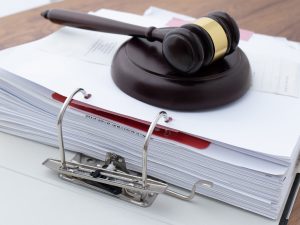 A gavel rests on top of a binder full of documents.