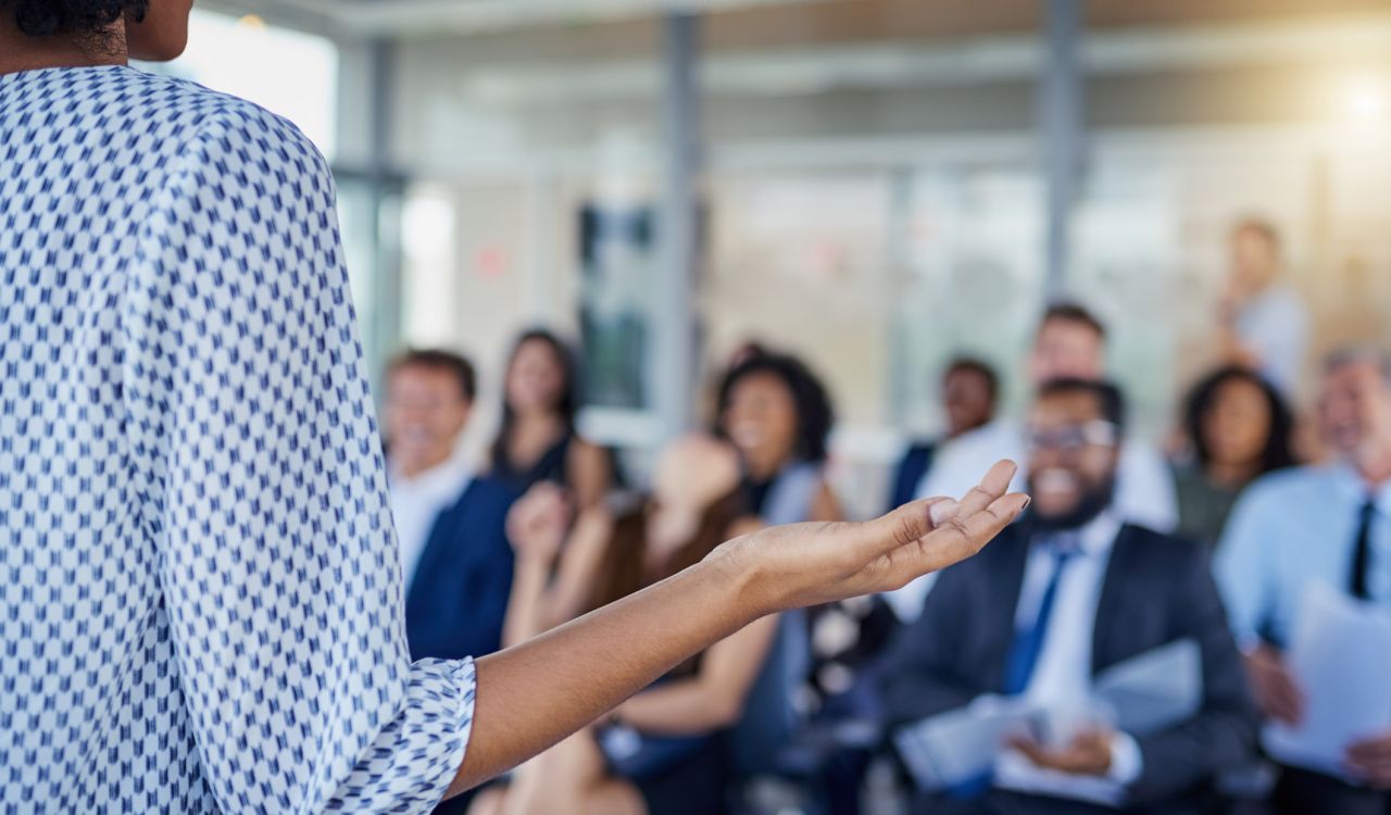 Close-up of the side of a business professional standing at the front of a room making a presentation to colleagues.