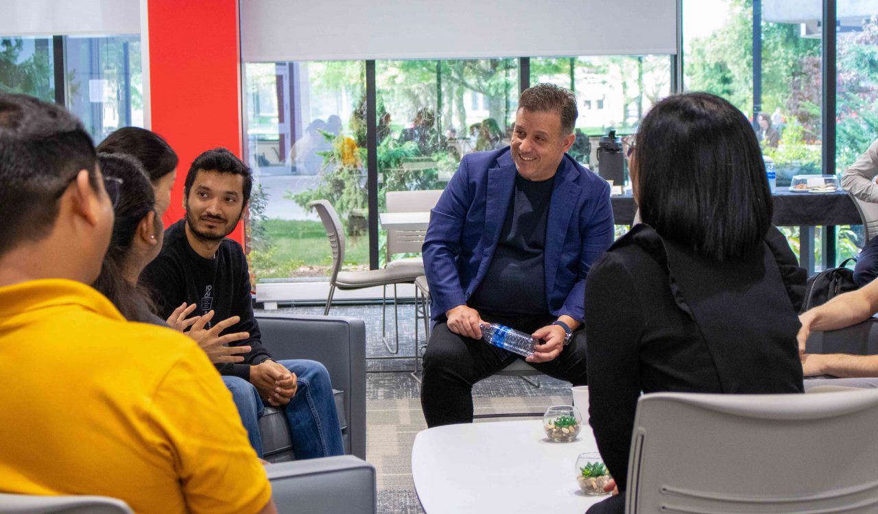 A group of people have a conversation in a university student lounge.