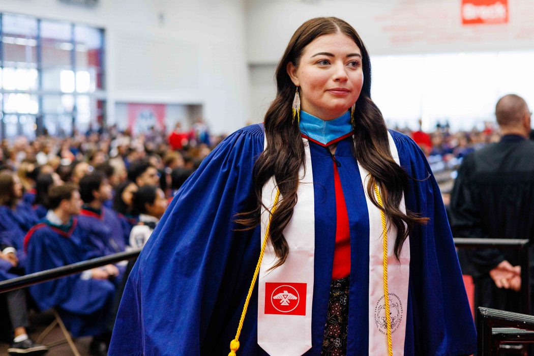 A woman wearing blue convocation robes crosses the convocation stage at Brock University.