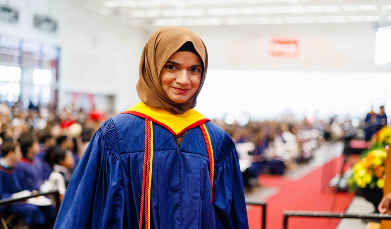 Marium Nur wears a blue convocation gown with red cords at Brock University’s Fall Convocation.