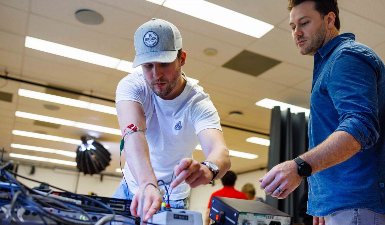 Two people work with tools and machinery in an office.