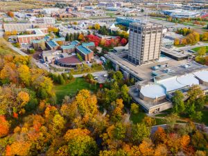 An aerial view of Brock University's main campus surrounded by trees with colourful fall leaves.