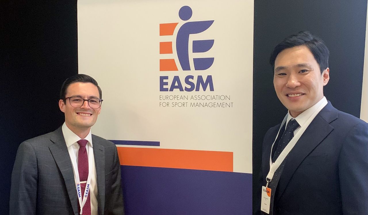 Two men, Erik Lachance and Changwook Kim, stand in front of a banner for European Association for Sport Management.