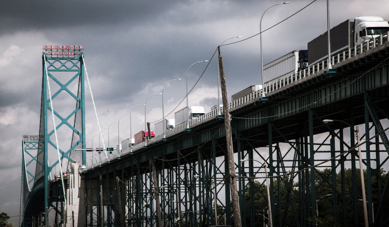 Transport trucks driving across a bridge crossing between the United States and Canada.