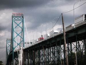 Transport trucks driving across a bridge crossing between the United States and Canada.