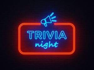 A neon sign reading "Trivia Night" hangs on a brick wall.