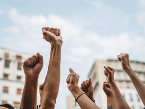 Fists of unseen striking demonstrators are raised against the sky