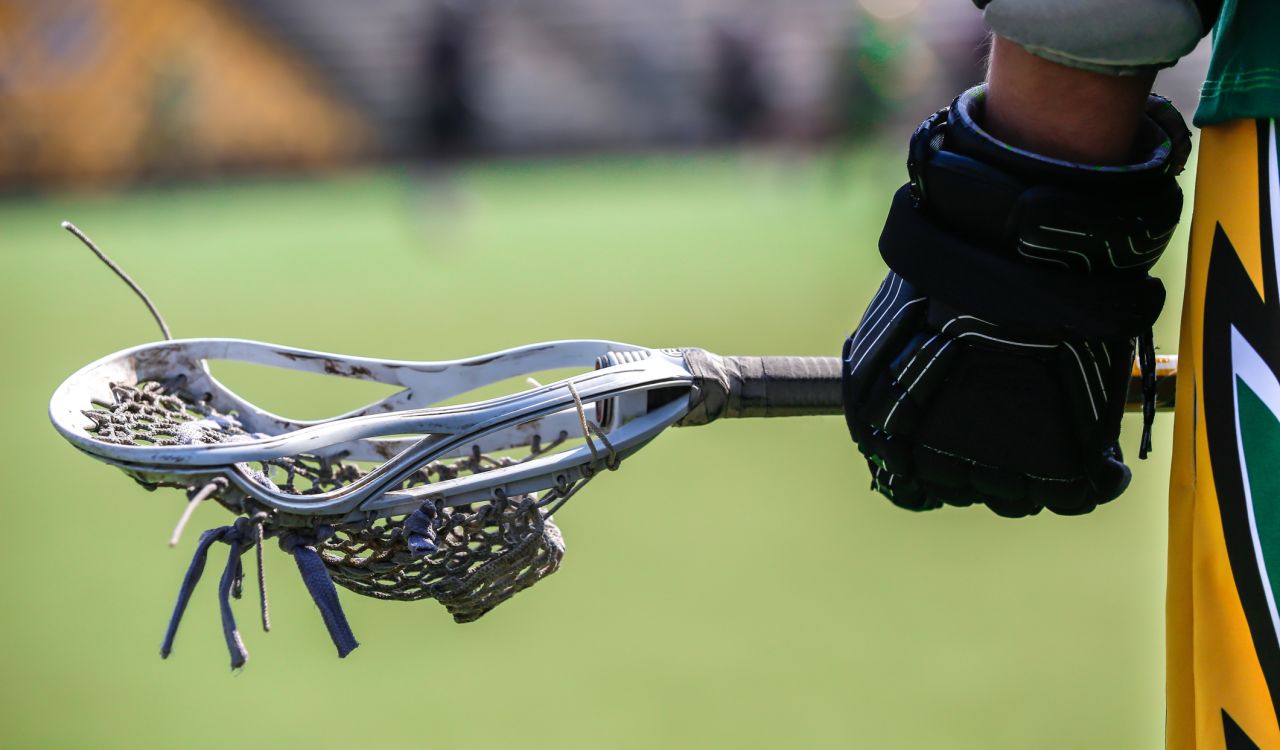 Close-up view of a gloved hand holding a lacrosse stick.