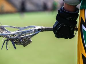 Close-up view of a gloved hand holding a lacrosse stick.