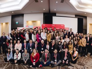 A large group of international education partners pictured in front of a stage in a hotel ballroom.