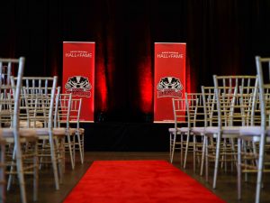 Empty chairs face two Brock Badgers Hall of Fame banners standing at the front of a room.