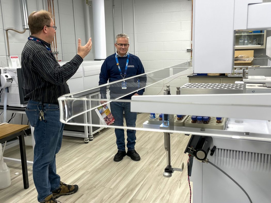 Two men standing in front of a piece of equipment.