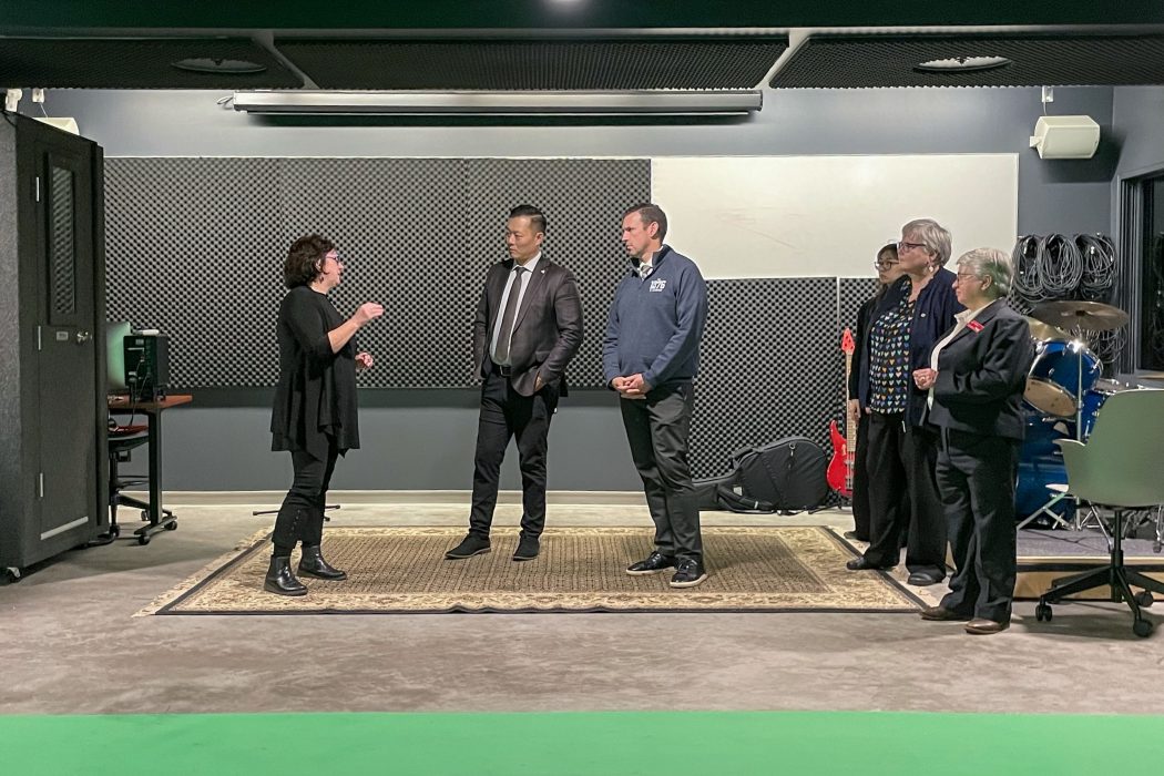 Six people stand in front of a black wall.