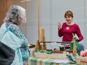 A woman helps a customer at a craft fair.