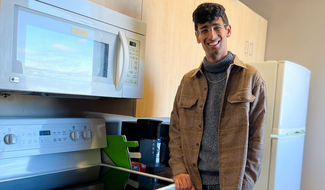 Brock University student Rachit Kapoor leans against an oven in a kitchenette.