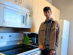 Brock University student Rachit Kapoor leans against an oven in a kitchenette.