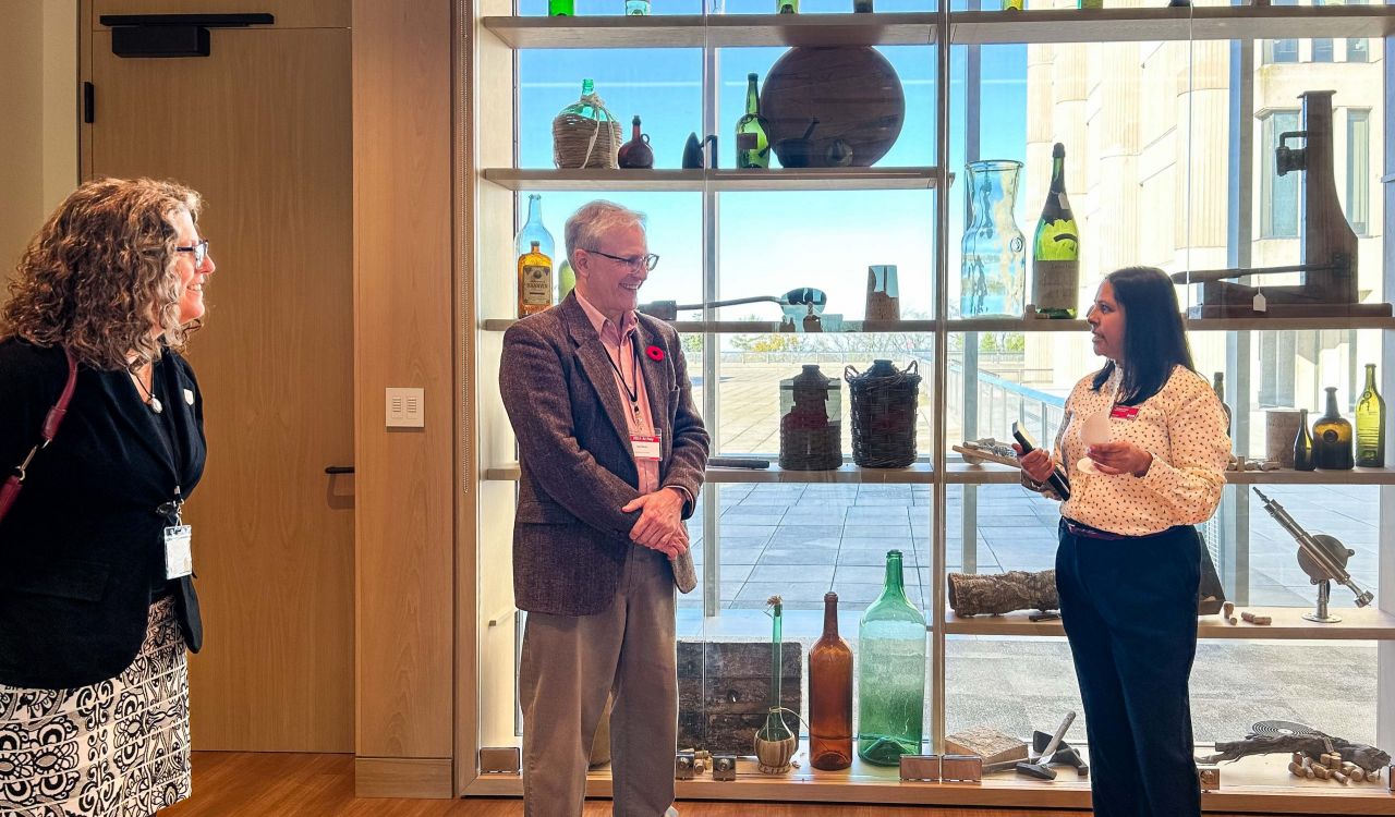 Three people stand in a room in front of a window.