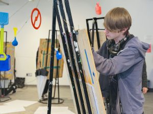 A person stands in an art studio drawing with a pencil at an easel.