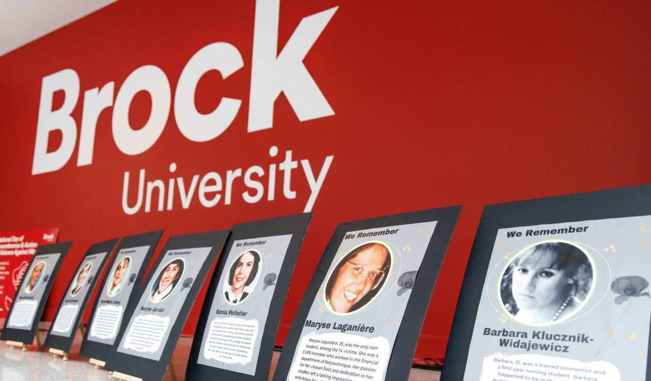 A row of photos of women displayed on low easels against a red wall.