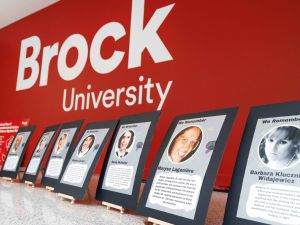 A row of photos of women displayed on low easels against a red wall.